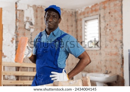 Portrait of african-american man construction worker with burnishing trowel. Royalty-Free Stock Photo #2434004145