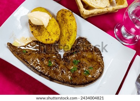 Tasty roast veal liver with baked potatoes served at plate, spanish dish Royalty-Free Stock Photo #2434004821