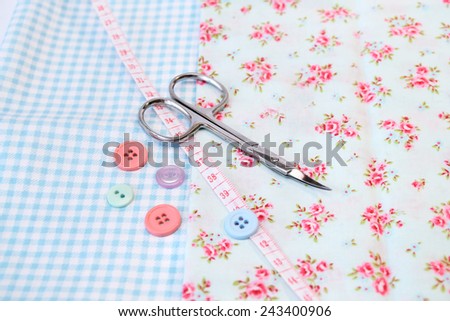 Sewing tools in a vintage fabric background with scissors and buttons