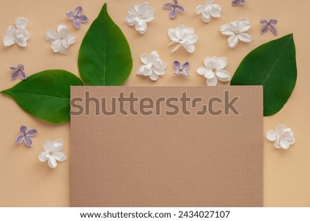Composition with empty envelope and beautiful spring lilac flowers on beige background. Mockup card invitation greeting card postcard copy space template. Branches of lilac blooming bouquet.  Royalty-Free Stock Photo #2434027107