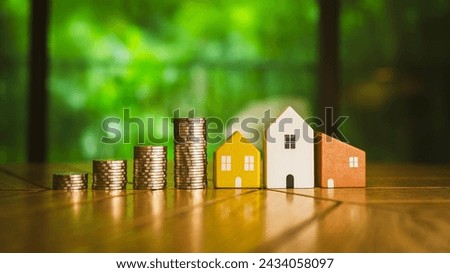 Wood house and row of coin money on wood table and , selective focus, Planning to buy property. Choose what's the best. A symbol for construction ,ecology, loan concepts.	