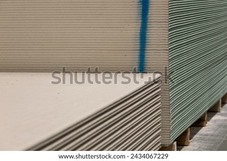 Stack of drywall in a construction warehouse or repair shop. Laying plasterboard panels. Sale of building materials.