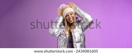 Lifestyle. Carefree funny amused fair-haired caucasian girl 25s having fun playing around mimicking bunny close eyes show tongue excited make animal ears palms on head standing purple background