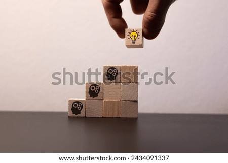 Concept creative idea and innovation. Hand picked wooden cube block with head human symbol and light bulb icon.