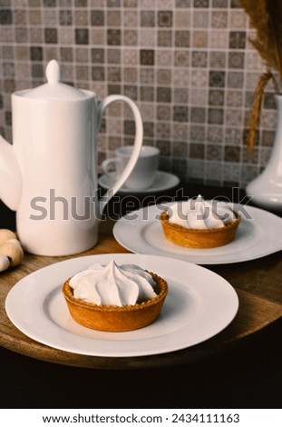 Lemon tart with zingy lemon curd topped with whipped lemon cream on white plate on wooden tray.