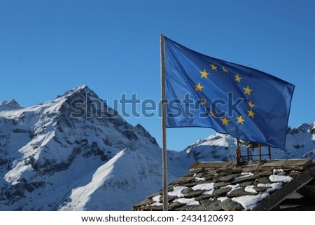 European flag flapping with the Alps in the background Royalty-Free Stock Photo #2434120693