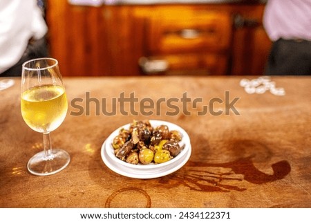 A glass of fino sherry with a side of mixed olives on a bar in a traditional Seville tavern. Royalty-Free Stock Photo #2434122371