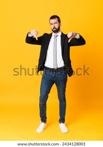 Full-length shot of business man over isolated yellow background showing thumb down