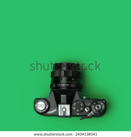 Top view of an old school analog reflex camera on an aquamarine green background with copy space Royalty-Free Stock Photo #2434138541