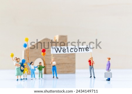 Miniature people holding "Welcome" signs at front of the home and copy space for text.