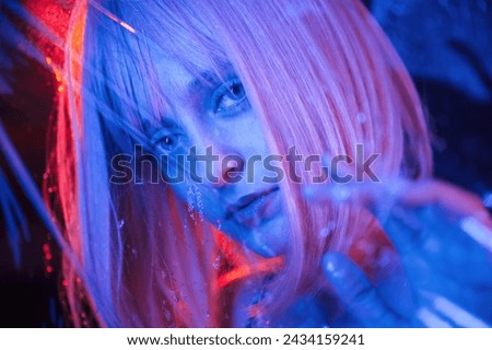 Posing for camera. Stylish woman with white hair is behind wet transparent plastic sheet.