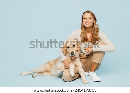 Full body smiling happy young owner woman wearing casual clothes sitting hug cuddle embrace her best friend retriever dog isolated on plain light blue background studio. Take care about pet concept Royalty-Free Stock Photo #2434178753