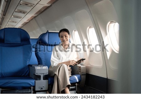 Traveling and technology. Flying at first class. Young business woman passenger using smartphone while sitting in airplane flight