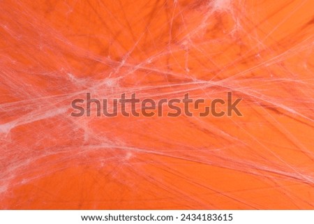 Creepy white cobweb hanging on orange background, closeup Royalty-Free Stock Photo #2434183615