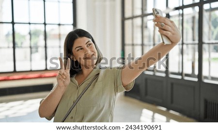 Young beautiful hispanic woman taking selfie with smartphone at new home