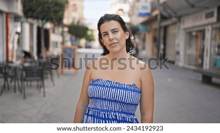 Young hispanic woman smiling happy looking at the camera at the street