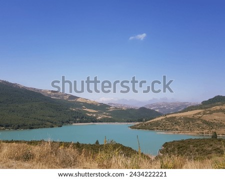 blue lake surrounded by muntains under a blue sky Royalty-Free Stock Photo #2434222221