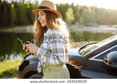 Happy woman on vacation taking selfie photo with smartphone near car. Stylish model on a car trip. Travel, blogging concept.