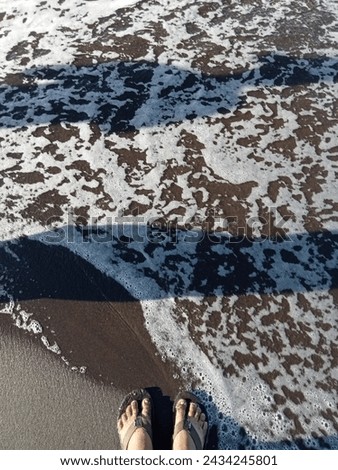 The small foam began to recede following the flow of the beach water which began to return to its place Royalty-Free Stock Photo #2434245801