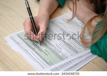 A woman fills out the Polish PIT tax declaration form, translation: Polish government annual tax settlement template Royalty-Free Stock Photo #2434248735
