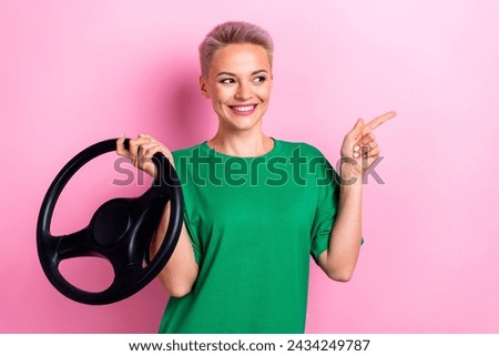 Portrait of charming positive lady hold wheel look indicate finger empty space isolated on pink color background