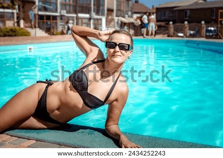Bikini-clad woman enjoys poolside relaxation. Poolside ambiance. Capturing woman's relaxed time near pool.