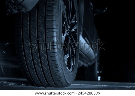 Low angle, back, rear view of a car, vehicle and its tires at the repairing shop. Concept of car maintenance service. empty Copy space. isolated on black background. night scene.