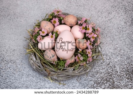 Happy Easter: Inscribed Easter egg with flowers and quail eggs in a nest. Italian inscription translates as Happy Easter. Royalty-Free Stock Photo #2434288789