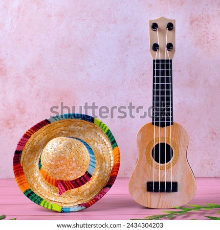 Mexican composition with copy space. Guitar and sombrero hat by the pink wall. Stereotypical attributes of Mexican culture. Celebrating Cinco de Mayo Royalty-Free Stock Photo #2434304203