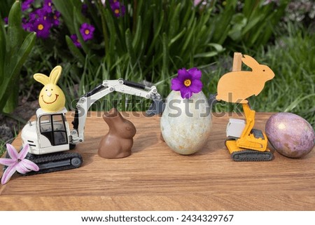 two models of toy excavators, Easter eggs, rabbits on a background of spring plants. Easter holiday concept for construction companies. postcard for business