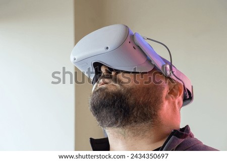 Bearded man in virtual reality headset looking up. Male in VR glasses. Modern technology for work, education and entertainment concept.