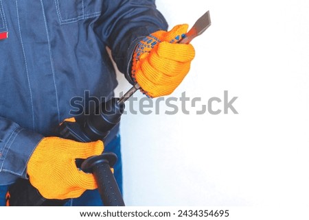 close-up. hands in protective gloves, hammer drill, installation of a chisel in a perforator. The concept of replacing the rotary drill. Royalty-Free Stock Photo #2434354695