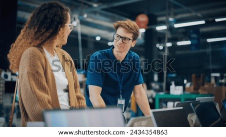Home Electronics Store Sales Consultant Comes to Assist a Young Woman in Selecting a Laptop. Customer Seeks High-Quality Work Device. Shopper Evaluates Modern Computer Options in a Retail Storefront Royalty-Free Stock Photo #2434354863