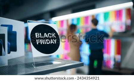 Close-Up of a Black Friday Sale Sign in a Home Electronics Department Store with a Range of Modern Smart TV Sets. Shoppers Explore Discounted Home Appliances in a Busy Retail Storefront Showroom