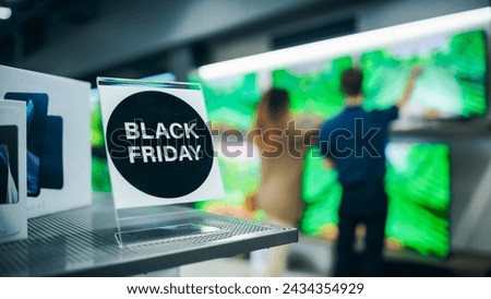 Close Up of a Black Friday Sale Sign in a Home Electronics Department Store with a Range of Modern Smart TV Sets. Shoppers Explore Discounted Home Appliances in a Busy Retail Storefront Showroom