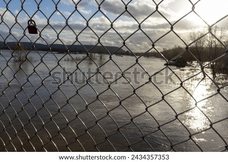 Valentine heart padlock attached to wire mesh fence. Love padlocks hanging on a bridge