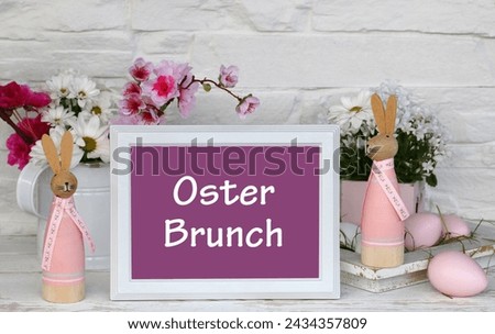 The text Easter Brunch written on a sign with Easter decorations and flowers. German inscription translates as Easter Brunch.