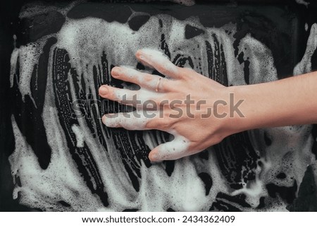 A woman's hand in soapy foam. The concept of a housewife or labor migration. Cheap, dirty work.