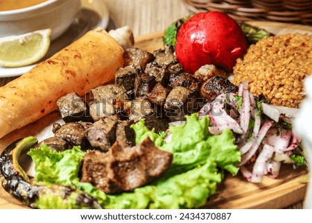 A wooden plate is pictured, featuring a savory assortment of meat and vegetables, ready to be enjoyed.
