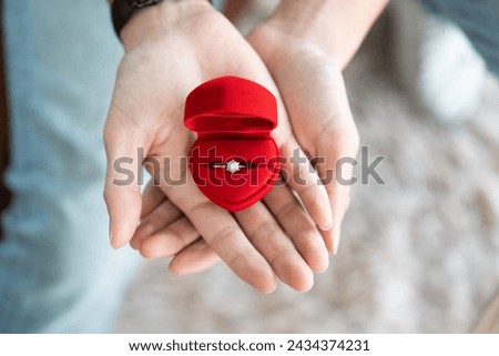 Boyfriend hand presenting a beautiful diamond engagement ring in a classic red velvet jewelry box symbol of love and commitment before surprise giving girlfriend in a special occasion