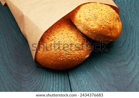burger buns in a package on a wooden background. appetizing buns with sesame in a paper package