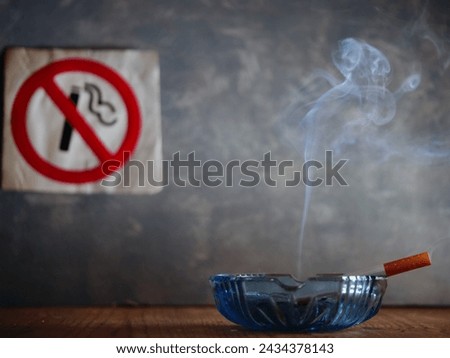Smoking cigarette in front of no smoking sign medium shot selective focus