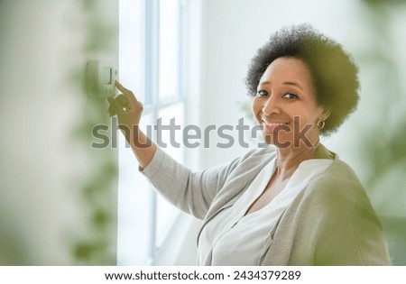 A senior black American woman at home thermostat setting