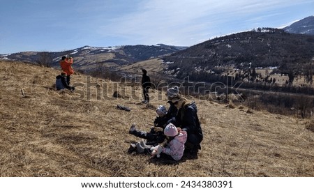 Adults and children on a mountain slope against the backdrop of mountains in the snow, tourists, family vacation. Photo.