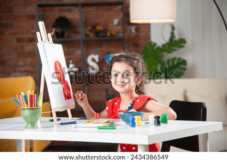 Indian little girl or kid Painting On Easel using brush and paint