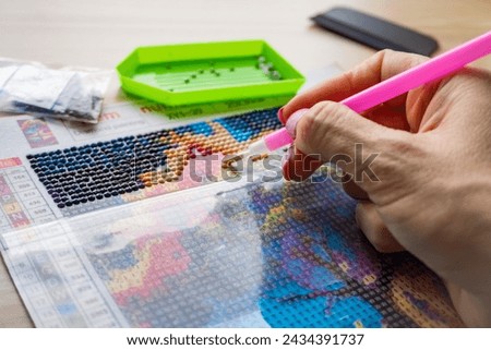 A woman draws a picture with beads. A set of images made of beads, handicrafts