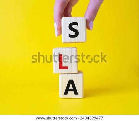 SLA - Service Level Agreement. Wooden cubes with word SLA. Businessman hand. Beautiful yellow background. Business and Service Level Agreement concept. Copy space.