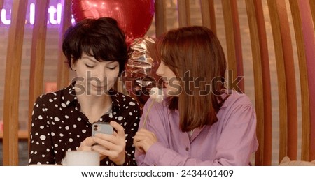 Couple dating in cafe. Woman affectionately brushes flower against partner's face. Delve into signs of attention, attraction, flirtation behavior. Connection and attraction in romantic relationships.