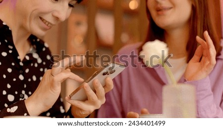 People browsing through photos, videos, news, memes, fashion trends, or entertaining clips found online. Women enthusiastically looking at phone screen while they discuss what they see, touch screen. 