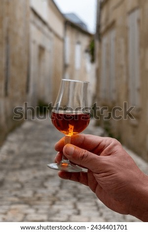 Tasting of aged in barrels cognac alcohol drink and view on old streets and houses in town Cognac, Grand Champagne, Charente, strong spirits distillation industry, France Royalty-Free Stock Photo #2434401701